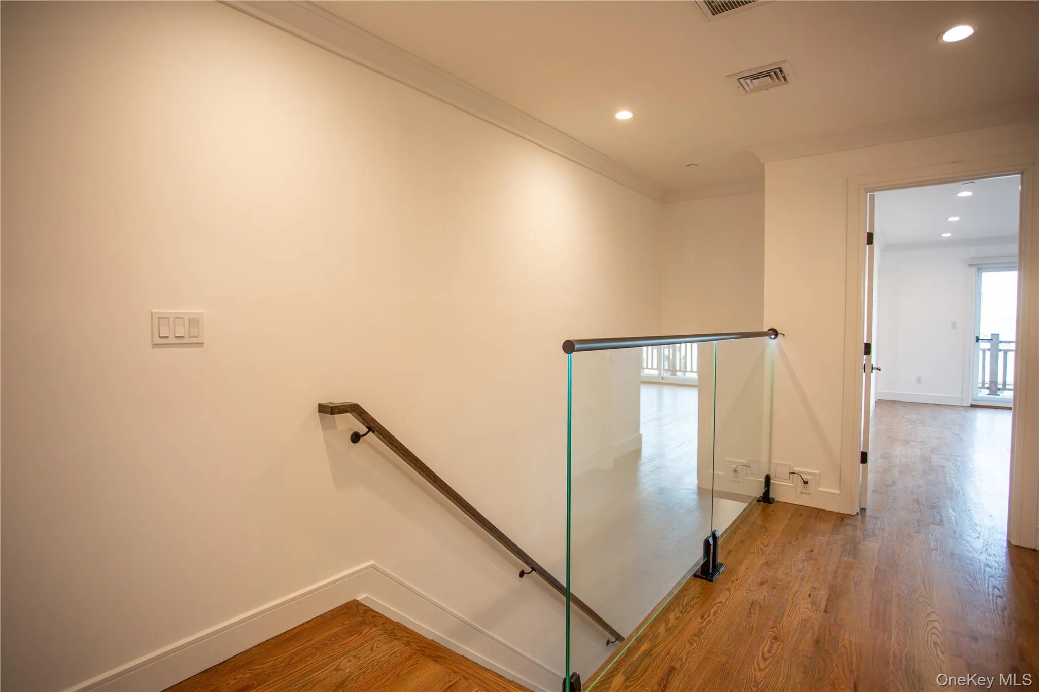 Hall with light wood-type flooring, recessed lighting, ornamental molding, and an upstairs landing Hall with light wood-type flooring, recessed lighting, ornamental molding, and an upstairs landing