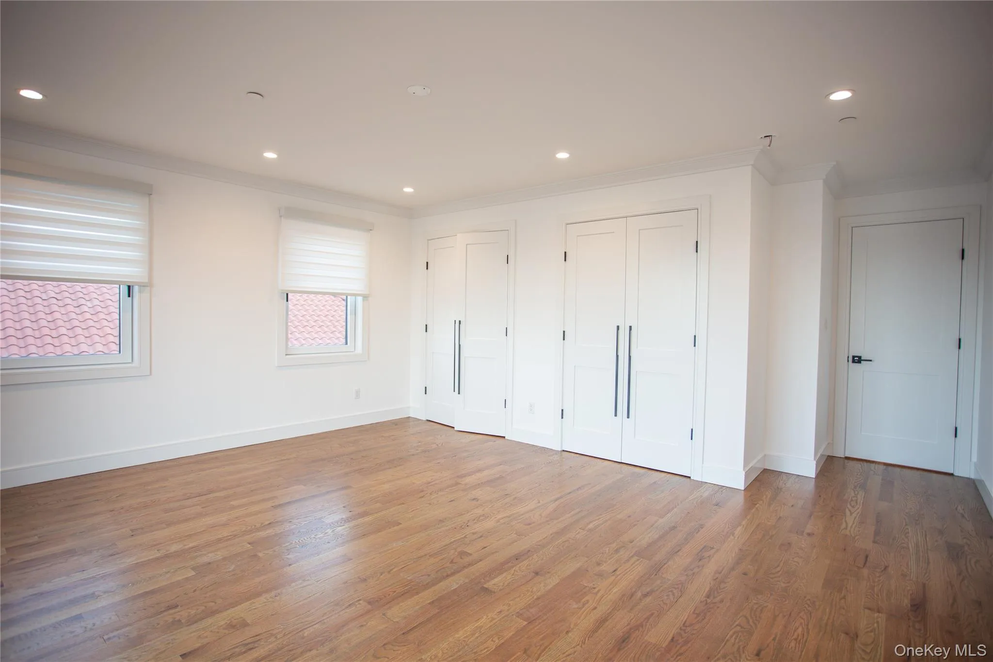 Unfurnished bedroom featuring multiple closets, crown molding, recessed lighting, and wood finished floors Unfurnished bedroom featuring multiple closets, crown molding, recessed lighting, and wood finished floors