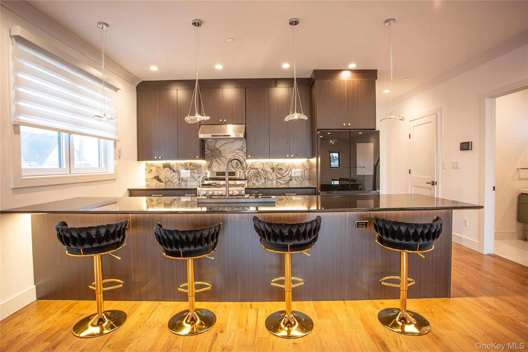Kitchen featuring tasteful backsplash, a peninsula, modern cabinets, decorative light fixtures, and a kitchen breakfast bar Kitchen featuring tasteful backsplash, a peninsula, modern cabinets, decorative light fixtures, and a kitchen breakfast bar