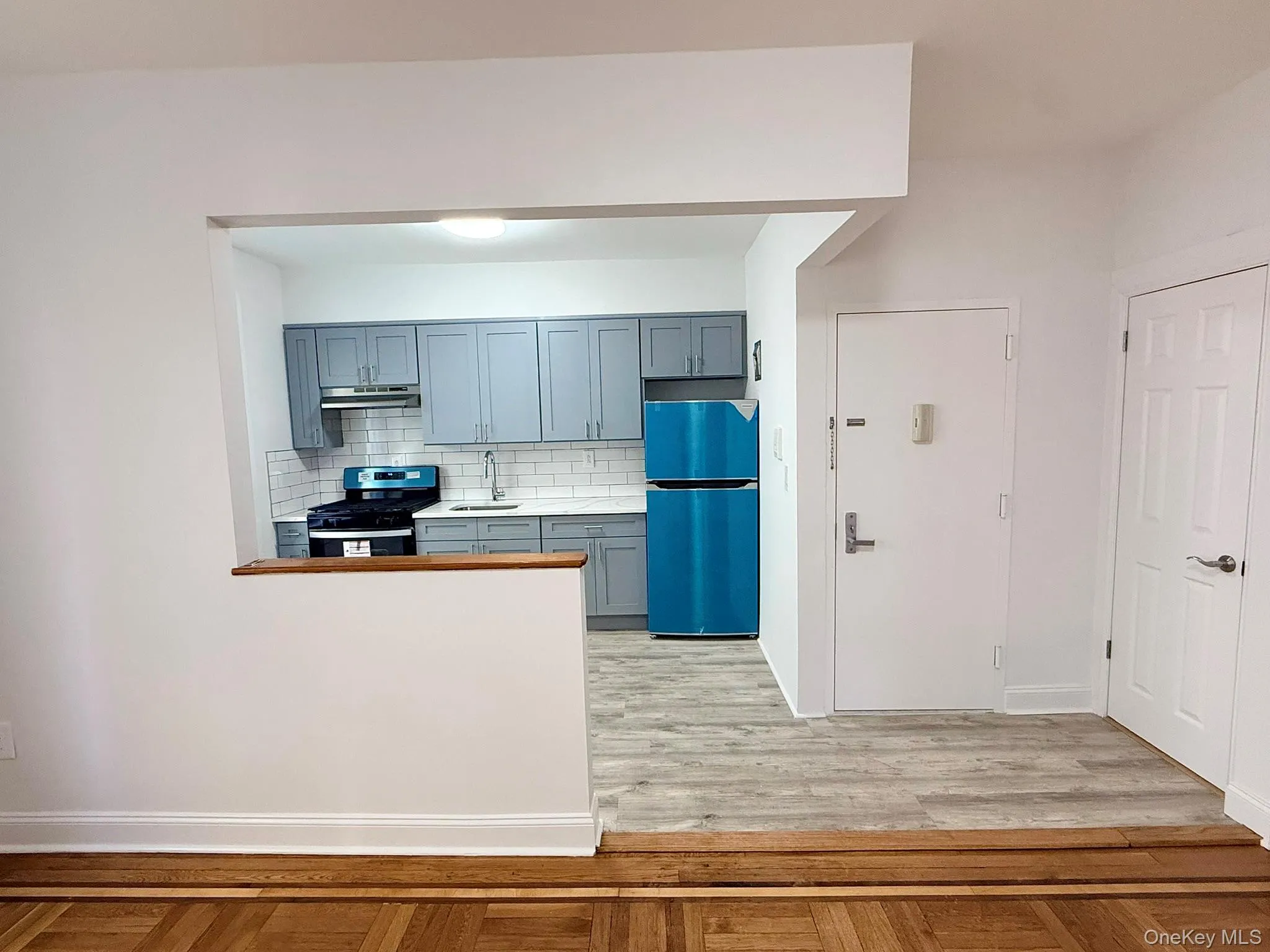 Kitchen featuring backsplash, light countertops, freestanding refrigerator, stainless steel range with gas stovetop, and gray cabinetry Kitchen featuring backsplash, light countertops, freestanding refrigerator, stainless steel range with gas stovetop, and gray cabinetry