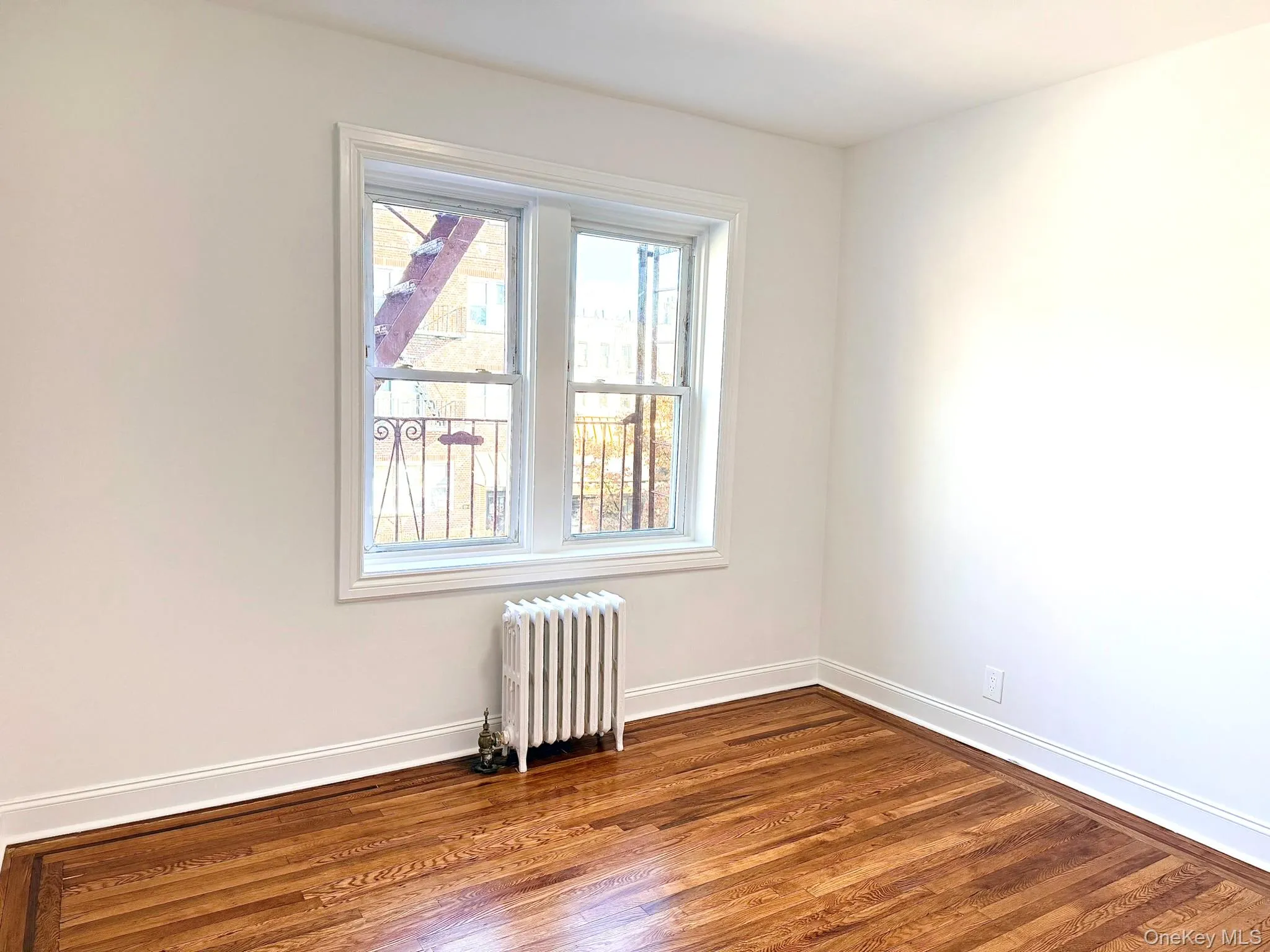 Spare room featuring radiator heating unit and dark wood-type flooring Spare room featuring radiator heating unit and dark wood-type flooring