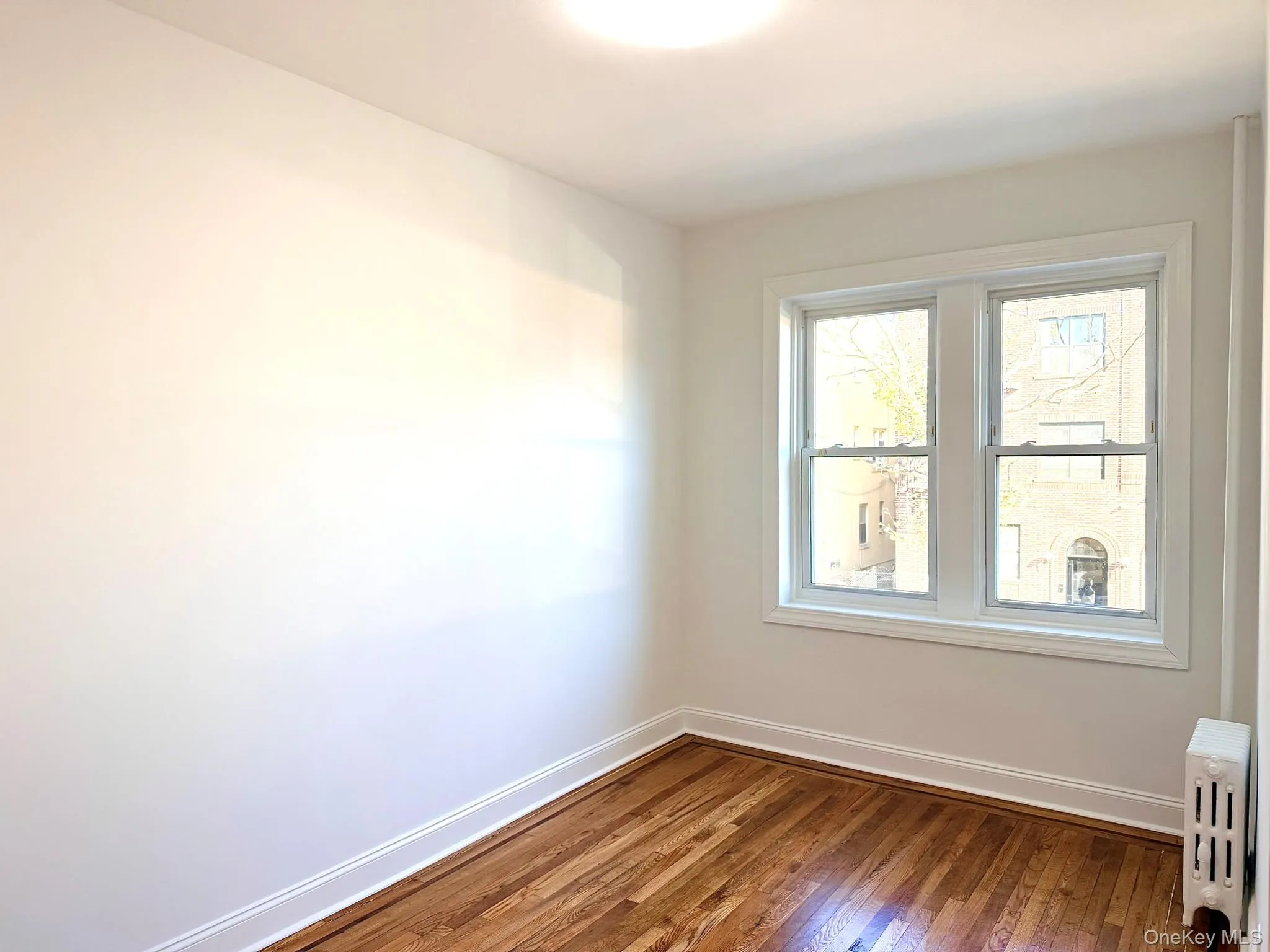 Unfurnished room featuring radiator and dark wood-style floors Unfurnished room featuring radiator and dark wood-style floors