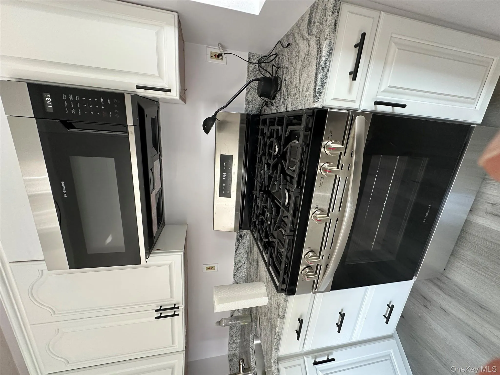 Kitchen with stainless steel gas range oven, white cabinets, and light stone countertops Kitchen with stainless steel gas range oven, white cabinets, and light stone countertops