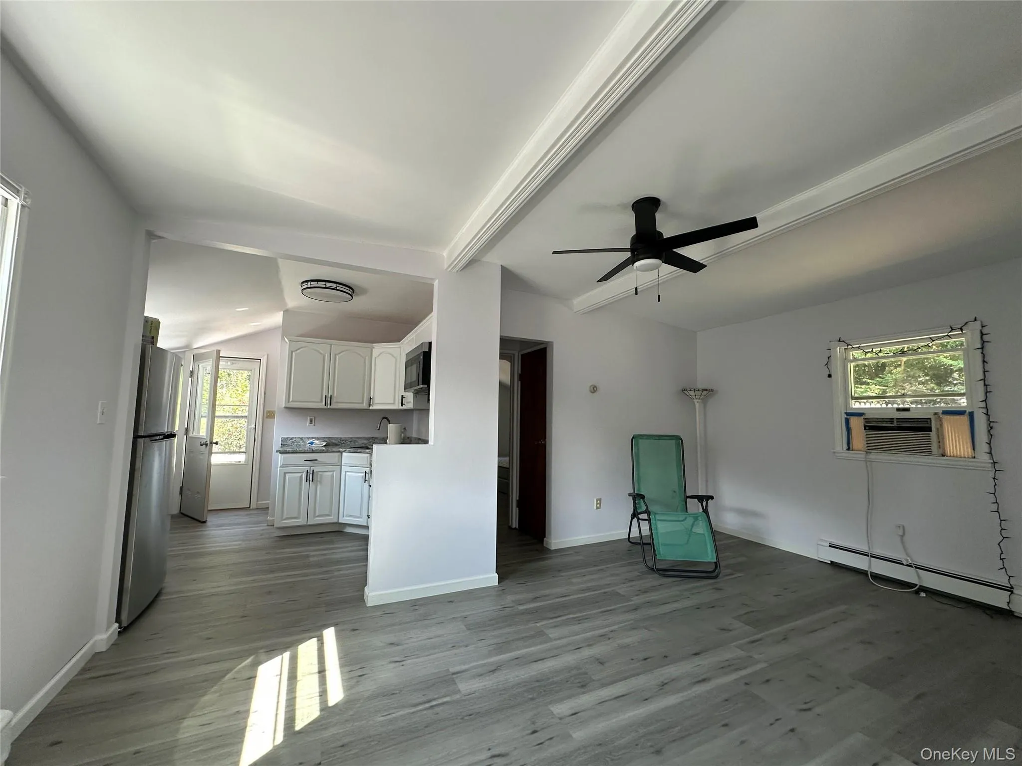 Unfurnished room featuring ceiling fan, healthy amount of natural light, light wood finished floors, and beamed ceiling Unfurnished room featuring ceiling fan, healthy amount of natural light, light wood finished floors, and beamed ceiling