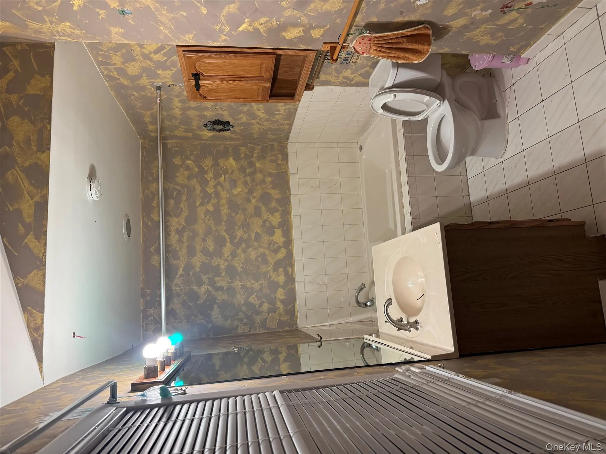 Full bathroom featuring wallpapered walls, vanity, light tile patterned flooring, and tiled shower / bath combo Full bathroom featuring wallpapered walls, vanity, light tile patterned flooring, and tiled shower / bath combo