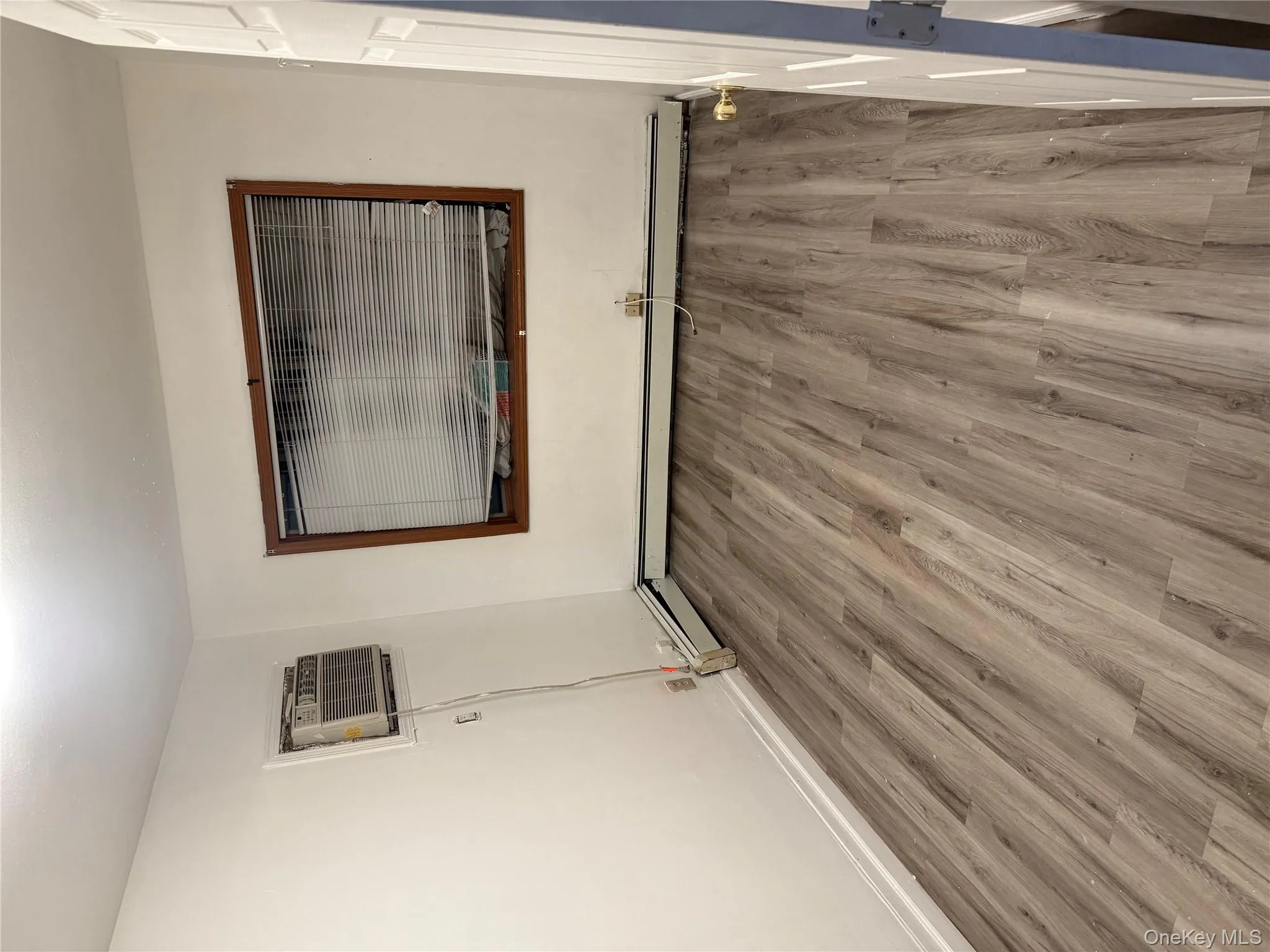 Unfurnished room with light wood finished floors, a wall mounted AC, and baseboard heating Unfurnished room with light wood finished floors, a wall mounted AC, and baseboard heating