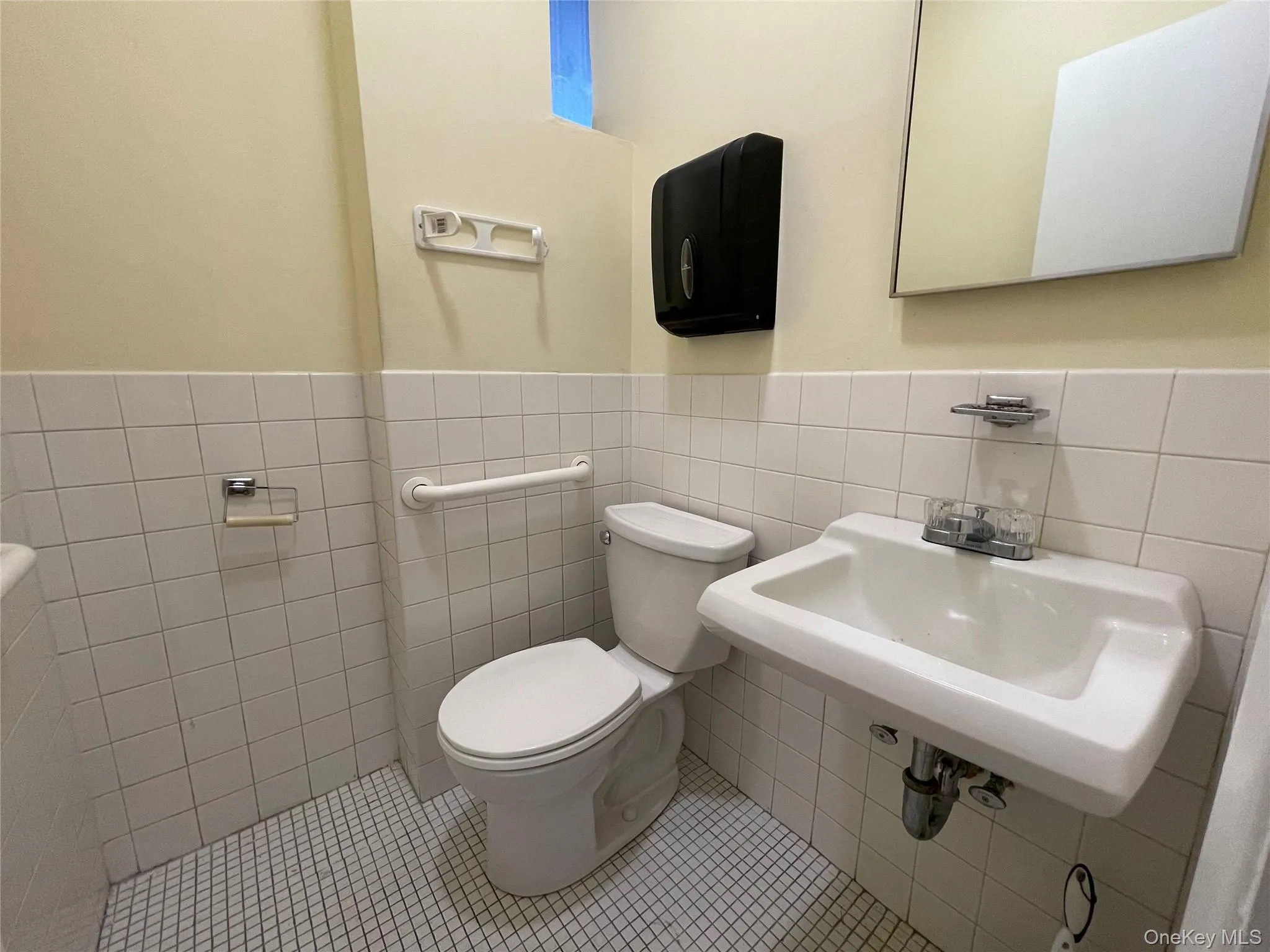 Half bath with tile walls, tile patterned floors, and a wainscoted wall Half bath with tile walls, tile patterned floors, and a wainscoted wall