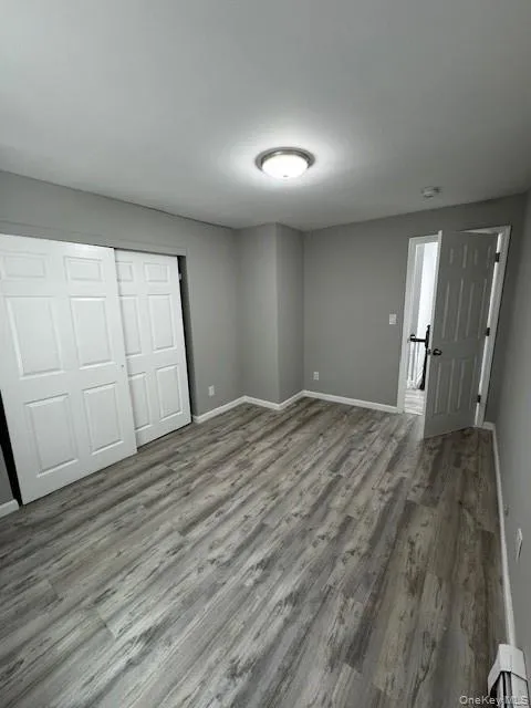 Unfurnished bedroom with a baseboard radiator, a closet, and wood-type flooring Unfurnished bedroom with a baseboard radiator, a closet, and wood-type flooring