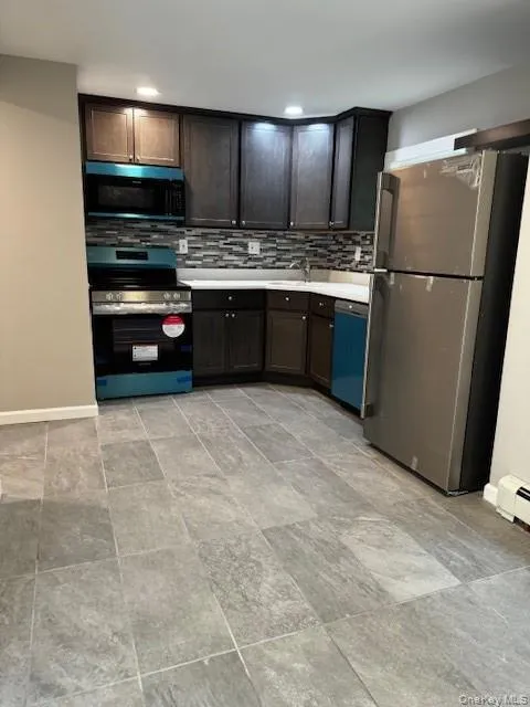 Kitchen with fridge, range, dishwashing machine, dark brown cabinets, and light tile floors Kitchen with fridge, range, dishwashing machine, dark brown cabinets, and light tile floors