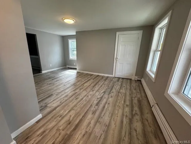 Empty room with a baseboard radiator and hardwood / wood-style flooring Empty room with a baseboard radiator and hardwood / wood-style flooring