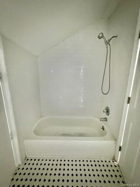 Bathroom with tiled shower / bath, tile flooring, and lofted ceiling Bathroom with tiled shower / bath, tile flooring, and lofted ceiling