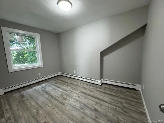 Empty room with baseboard heating and hardwood / wood-style flooring Empty room with baseboard heating and hardwood / wood-style flooring