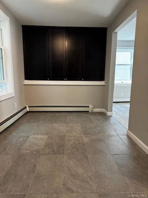 Tiled empty room featuring a wealth of natural light and baseboard heating Tiled empty room featuring a wealth of natural light and baseboard heating