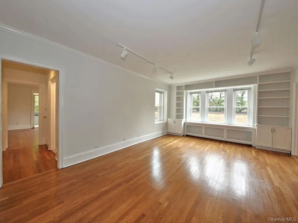 Empty room with track lighting, built in features, and light wood-type flooring Empty room with track lighting, built in features, and light wood-type flooring