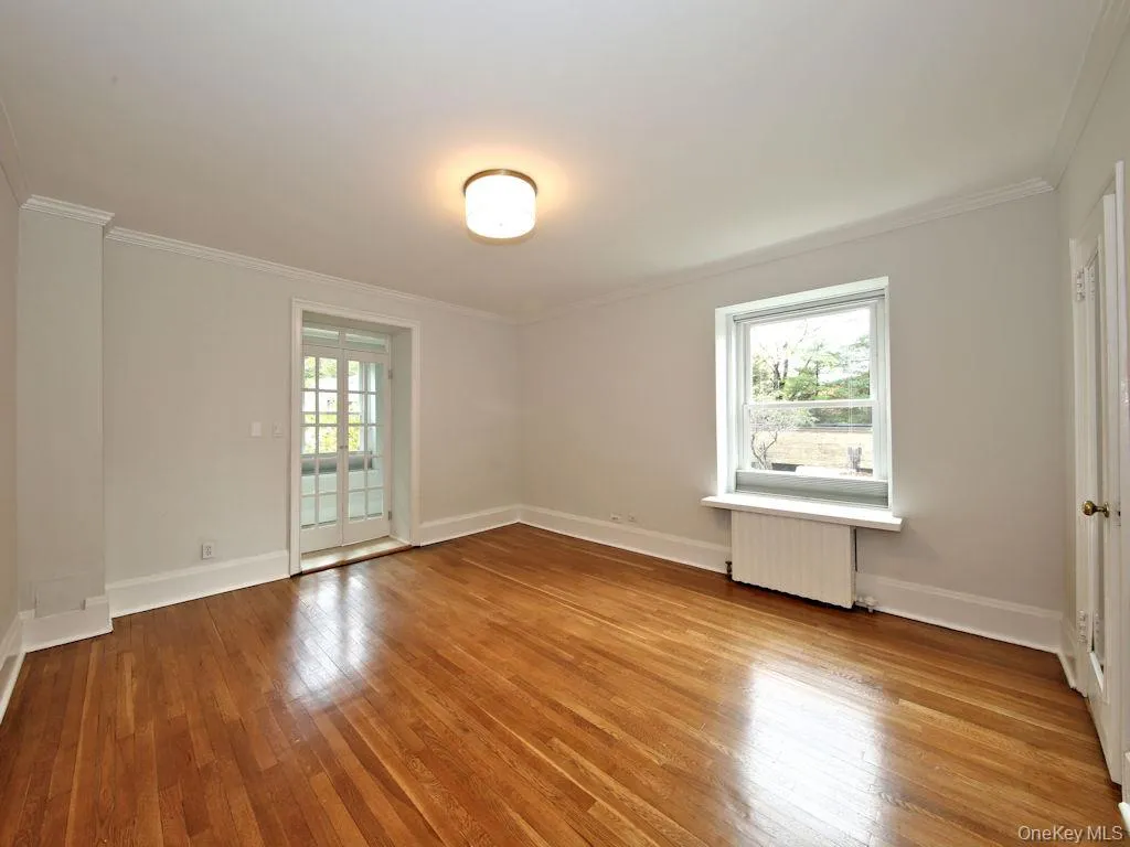 Empty room featuring light wood-style flooring, radiator, and crown molding Empty room featuring light wood-style flooring, radiator, and crown molding