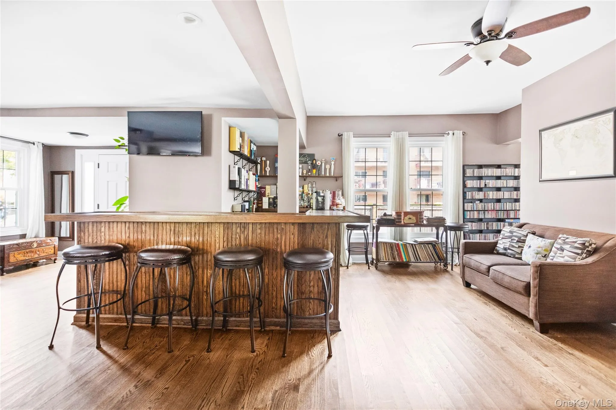 Indoor dry bar featuring light wood-type flooring, a ceiling fan, and beamed ceiling Indoor dry bar featuring light wood-type flooring, a ceiling fan, and beamed ceiling