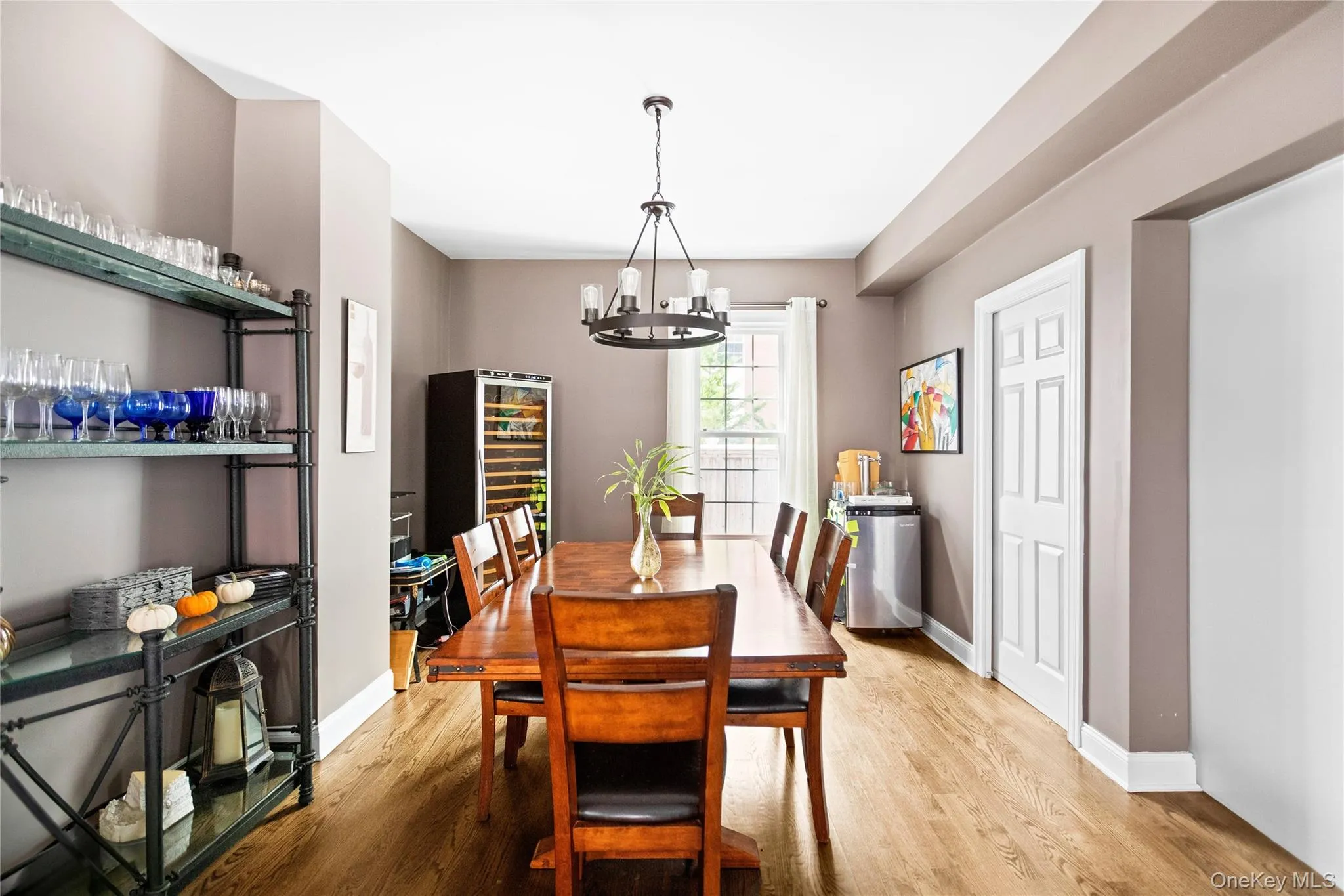 Dining area featuring light wood finished floors, wine cooler, and a chandelier Dining area featuring light wood finished floors, wine cooler, and a chandelier