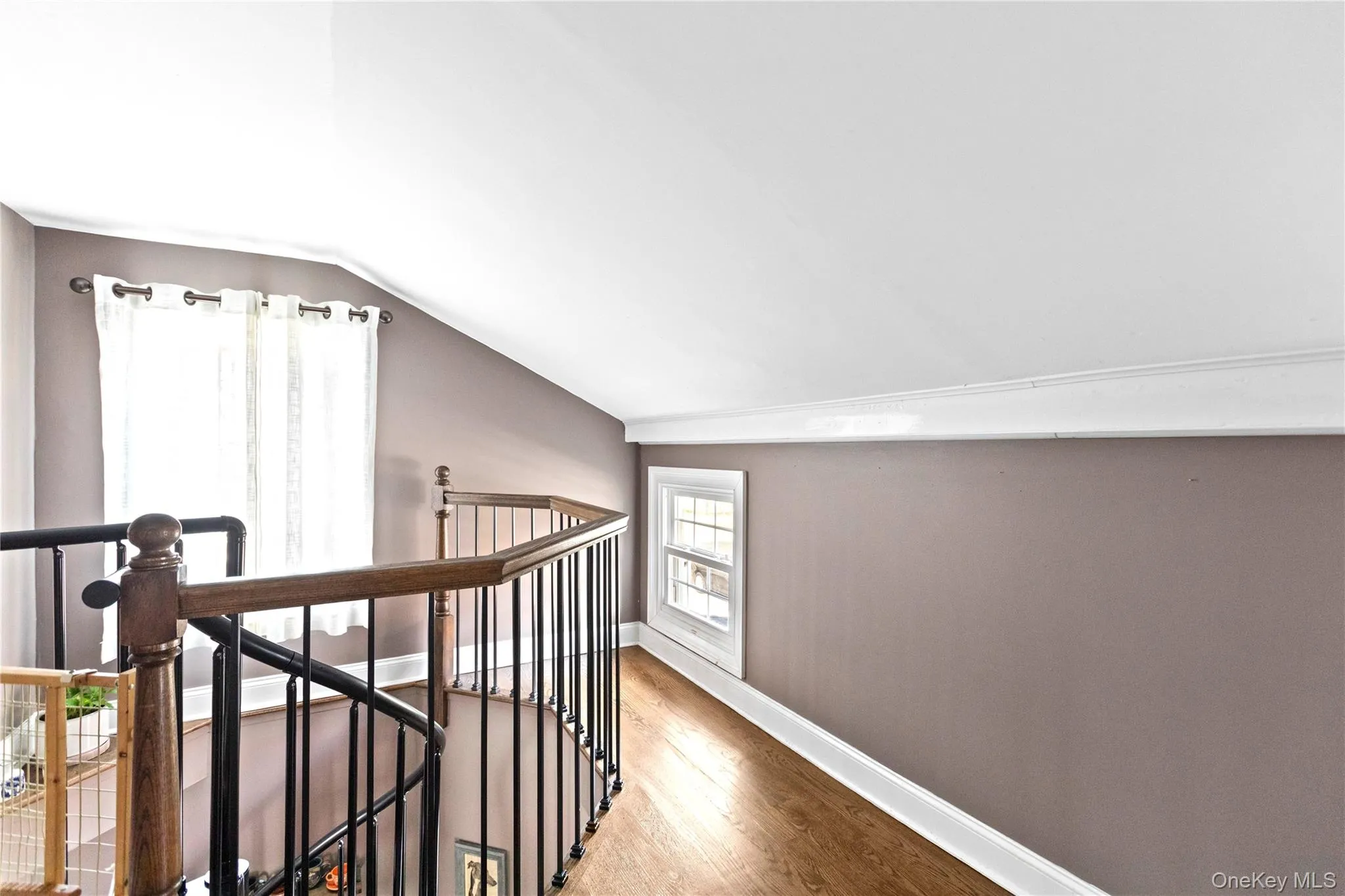 Corridor with lofted ceiling, an upstairs landing, and wood finished floors Corridor with lofted ceiling, an upstairs landing, and wood finished floors
