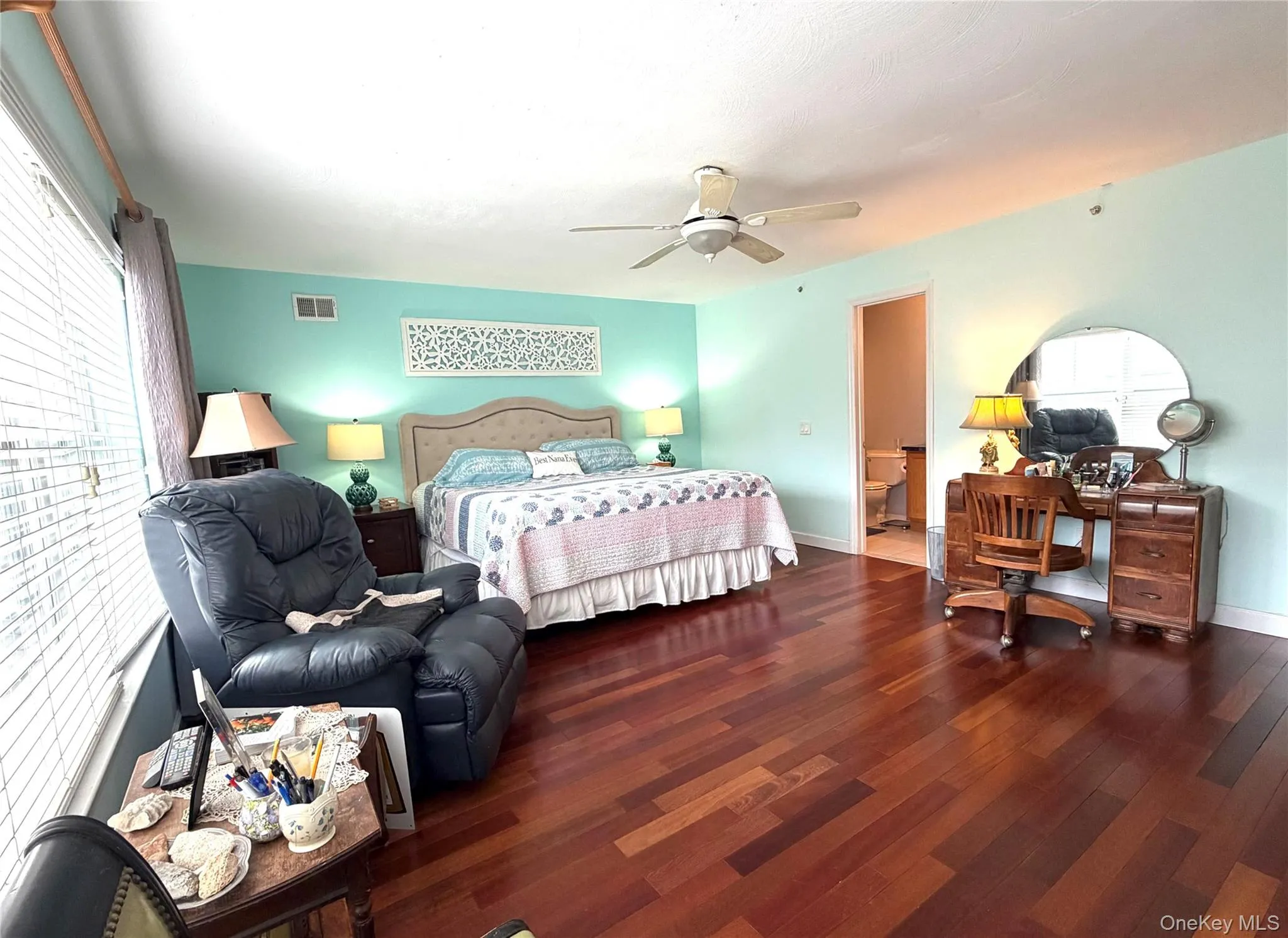 Bedroom with wood finished floors, ensuite bath, a desk, and ceiling fan Bedroom with wood finished floors, ensuite bath, a desk, and ceiling fan