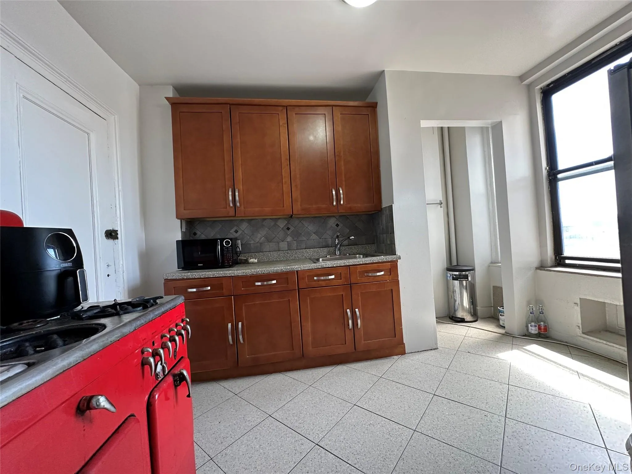 Kitchen with tasteful backsplash, a sink, brown cabinetry, and black microwave Kitchen with tasteful backsplash, a sink, brown cabinetry, and black microwave