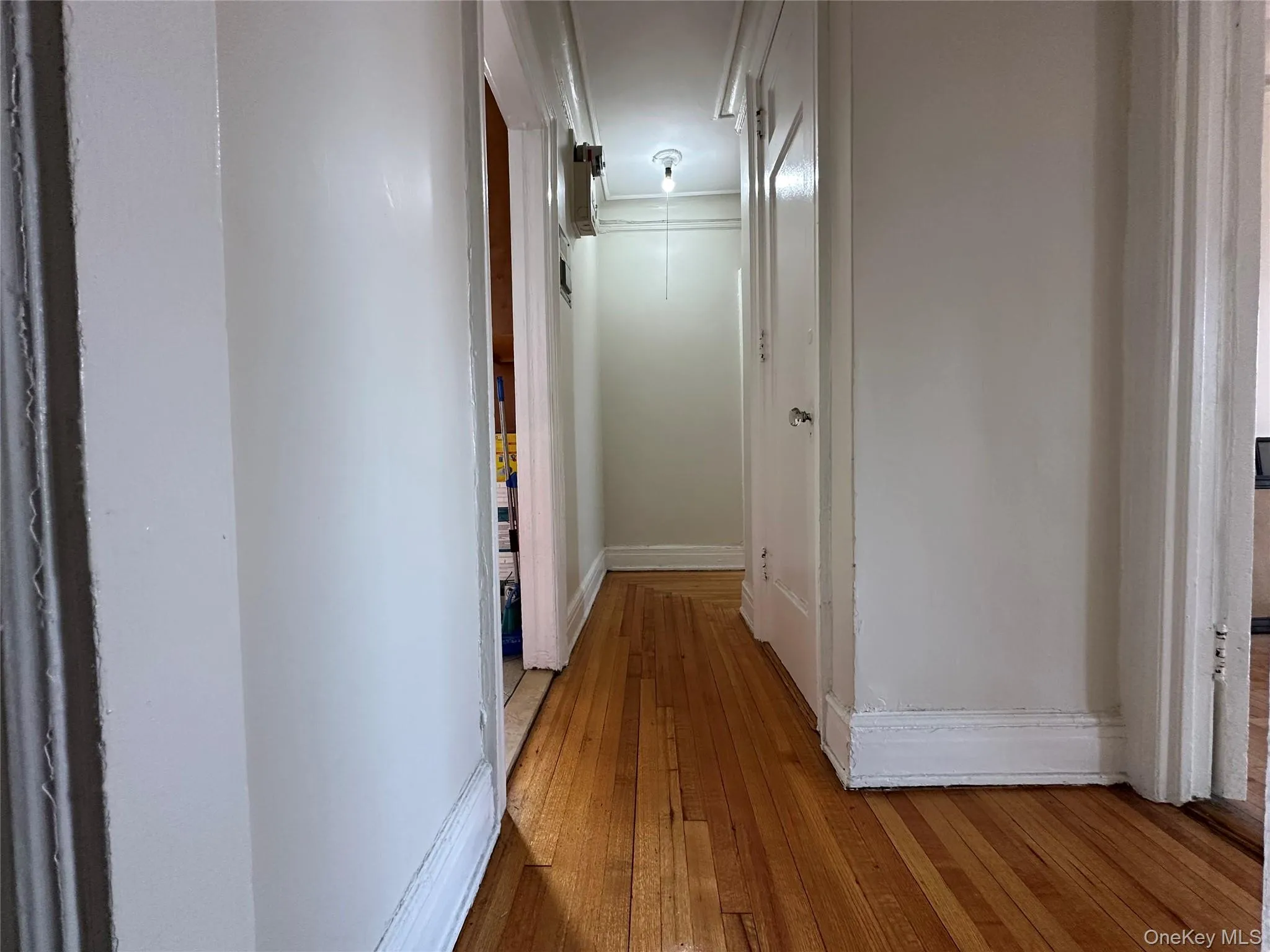 Hallway featuring light wood-type flooring, attic access, and baseboards Hallway featuring light wood-type flooring, attic access, and baseboards