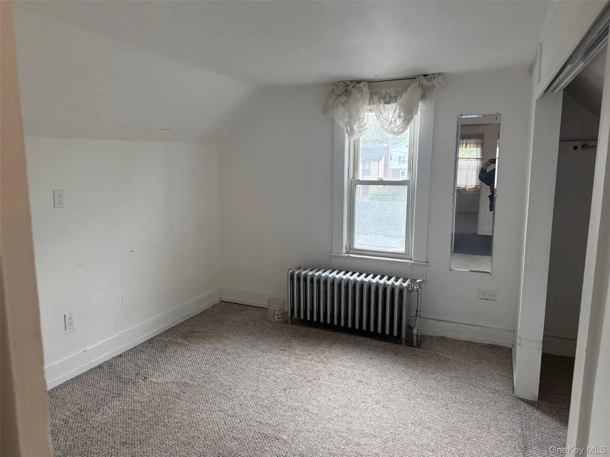 Storage space with carpet floors, radiator heating unit, and lofted ceiling Storage space with carpet floors, radiator heating unit, and lofted ceiling