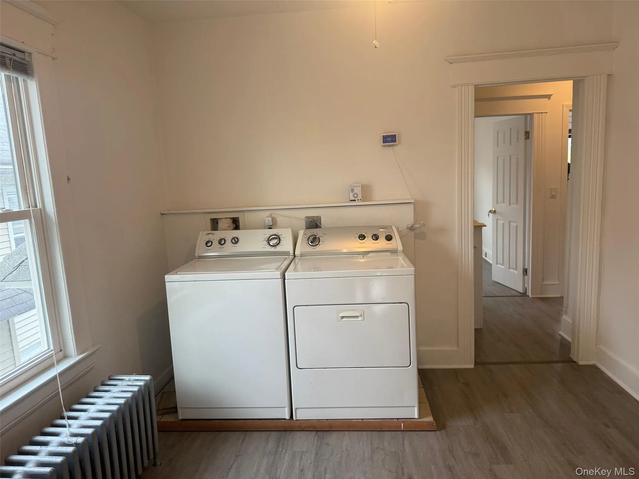Laundry room featuring radiator heating unit, light wood finished floors, healthy amount of natural light, and separate washer and dryer Laundry room featuring radiator heating unit, light wood finished floors, healthy amount of natural light, and separate washer and dryer