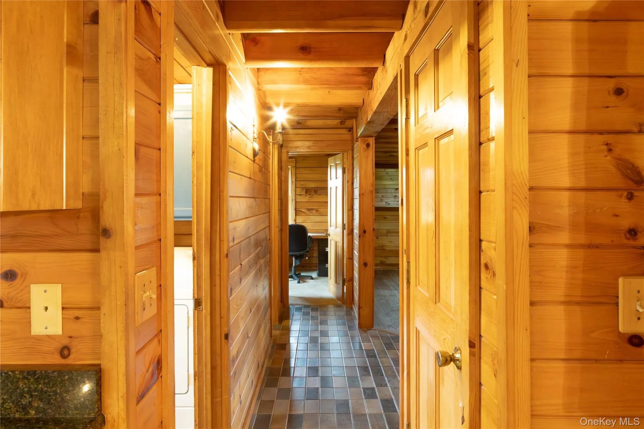 Corridor featuring wood walls, an office area, and tile patterned floors Corridor featuring wood walls, an office area, and tile patterned floors