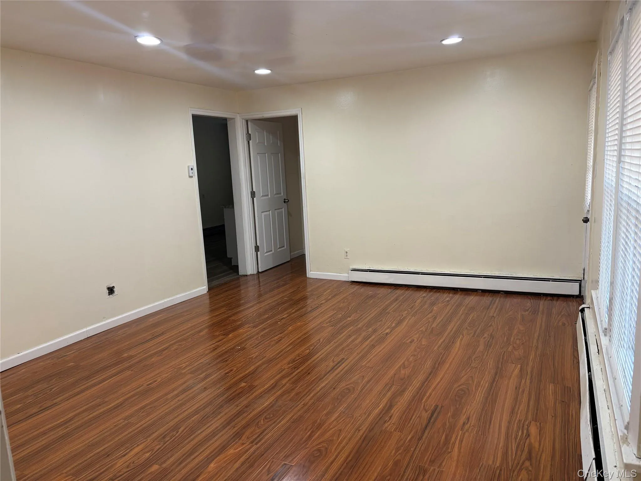 living room featuring dark wood-style floors, recessed lighting, a baseboard heating unit, and baseboard heating living room featuring dark wood-style floors, recessed lighting, a baseboard heating unit, and baseboard heating