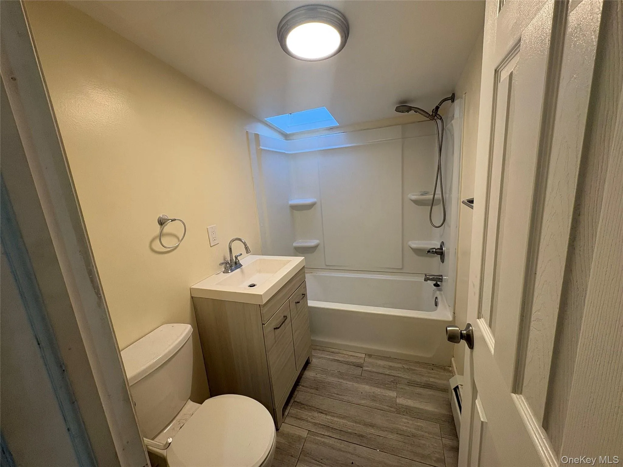 Bathroom featuring vanity, bathing tub / shower combination, and dark wood-style floors Bathroom featuring vanity, bathing tub / shower combination, and dark wood-style floors