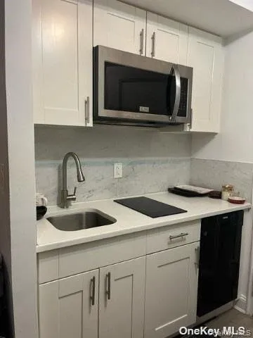 Kitchen featuring white cabinetry, black appliances, light stone countertops, and dark wood finished floors Kitchen featuring white cabinetry, black appliances, light stone countertops, and dark wood finished floors