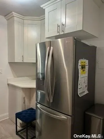 Kitchen featuring stainless steel fridge, white cabinets, and light wood-type flooring Kitchen featuring stainless steel fridge, white cabinets, and light wood-type flooring