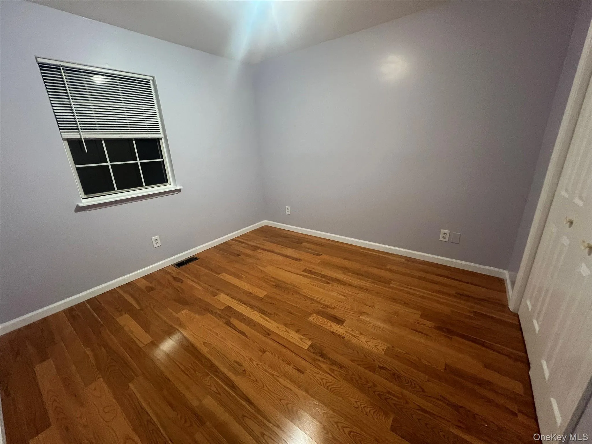 Unfurnished room with wood finished floors and baseboards Unfurnished room with wood finished floors and baseboards
