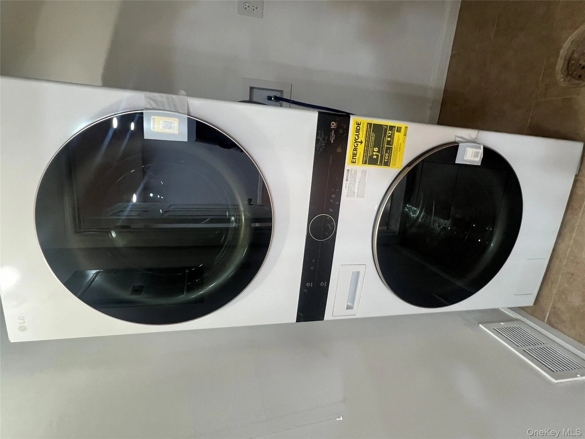 Washroom featuring stacked washer / drying machine and tile patterned flooring Washroom featuring stacked washer / drying machine and tile patterned flooring