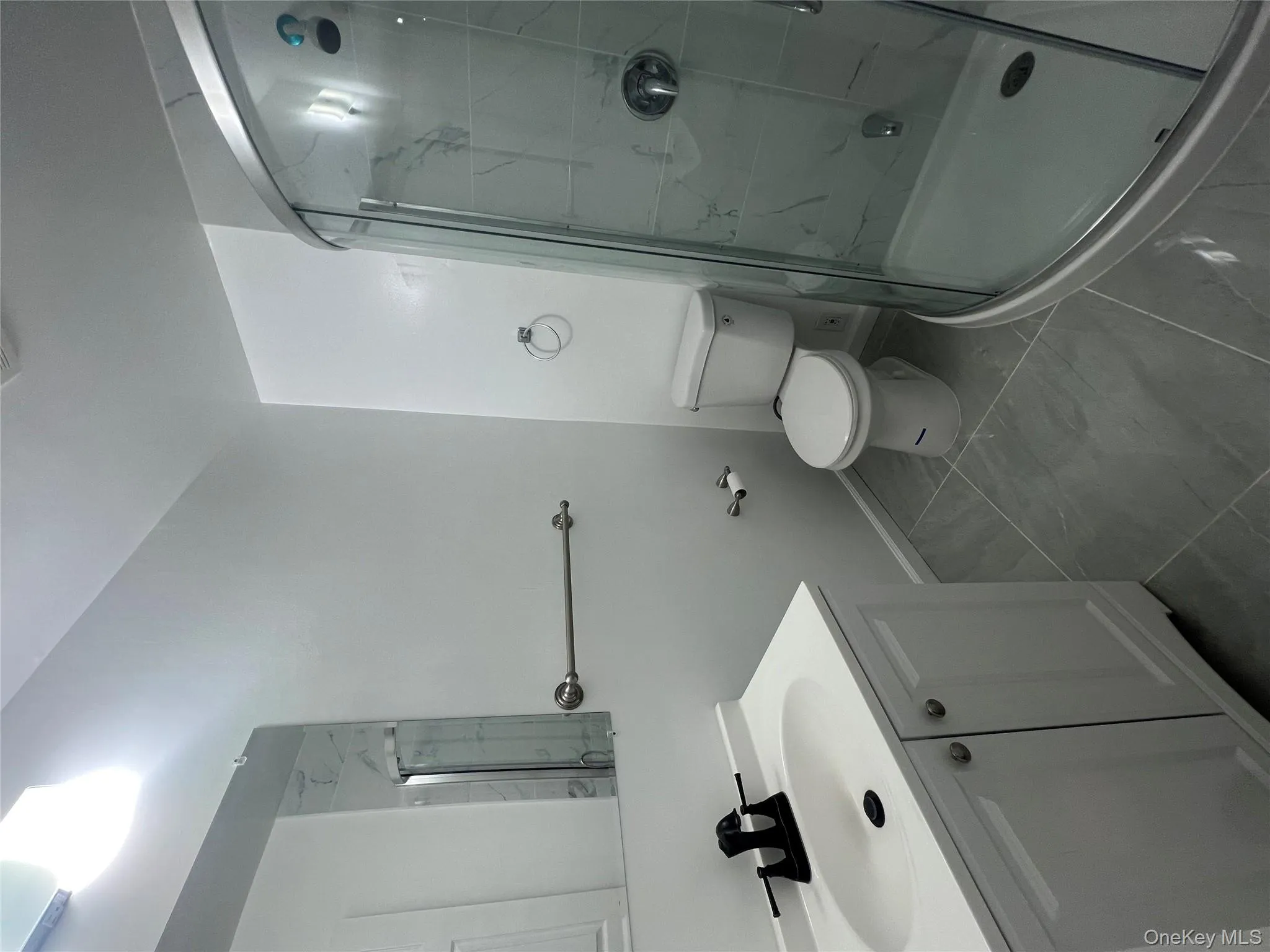 Bathroom featuring a stall shower, vanity, and marble finish floors Bathroom featuring a stall shower, vanity, and marble finish floors