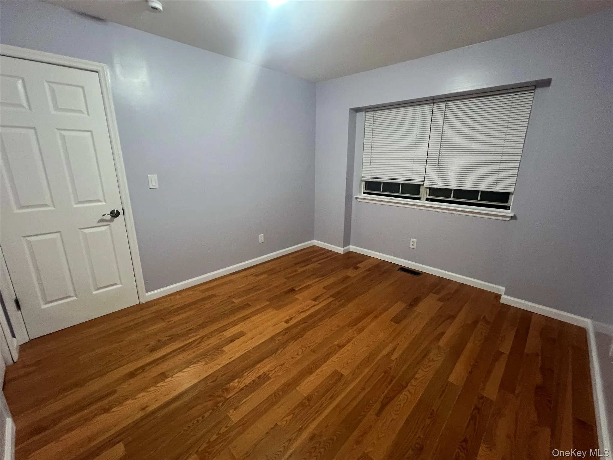 Empty room featuring wood finished floors and baseboards Empty room featuring wood finished floors and baseboards
