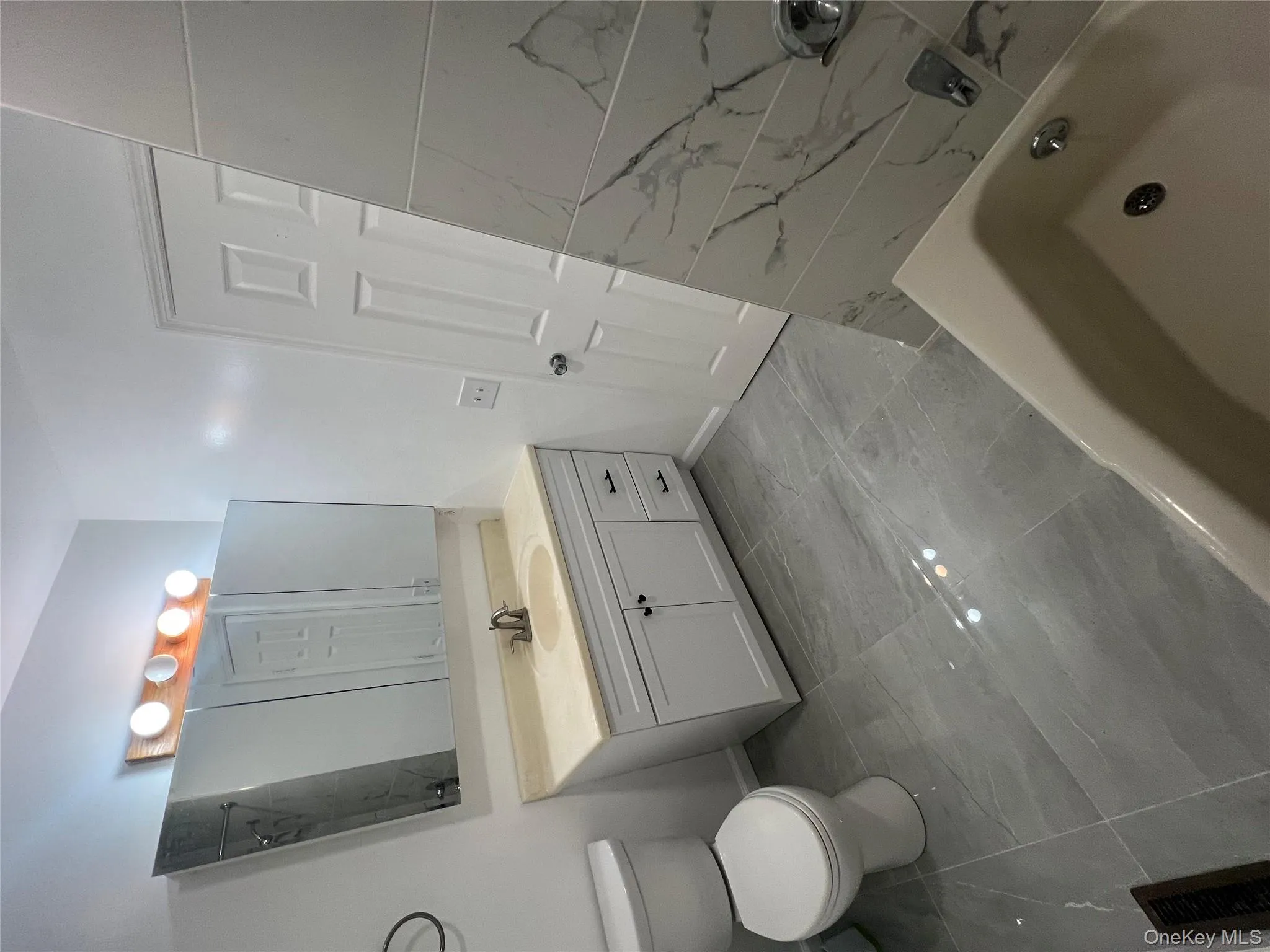 Bathroom featuring marble look tiles, vanity, and shower / bath combination Bathroom featuring marble look tiles, vanity, and shower / bath combination