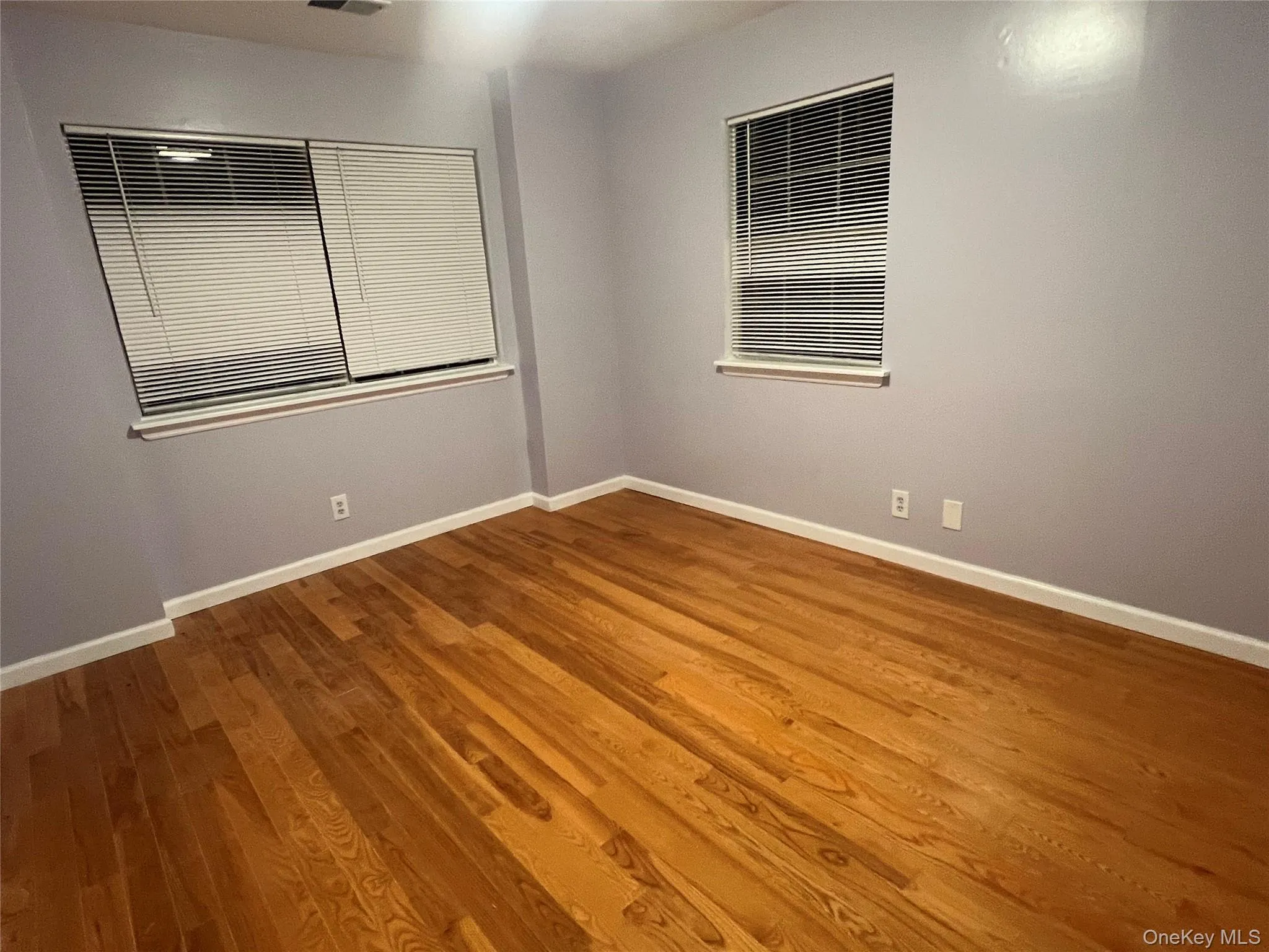 Empty room featuring wood finished floors and baseboards Empty room featuring wood finished floors and baseboards