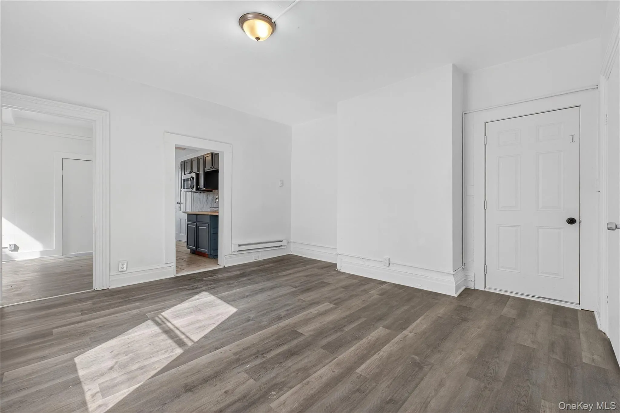 Unfurnished bedroom with dark wood-type flooring, a baseboard radiator, and ensuite bathroom Unfurnished bedroom with dark wood-type flooring, a baseboard radiator, and ensuite bathroom