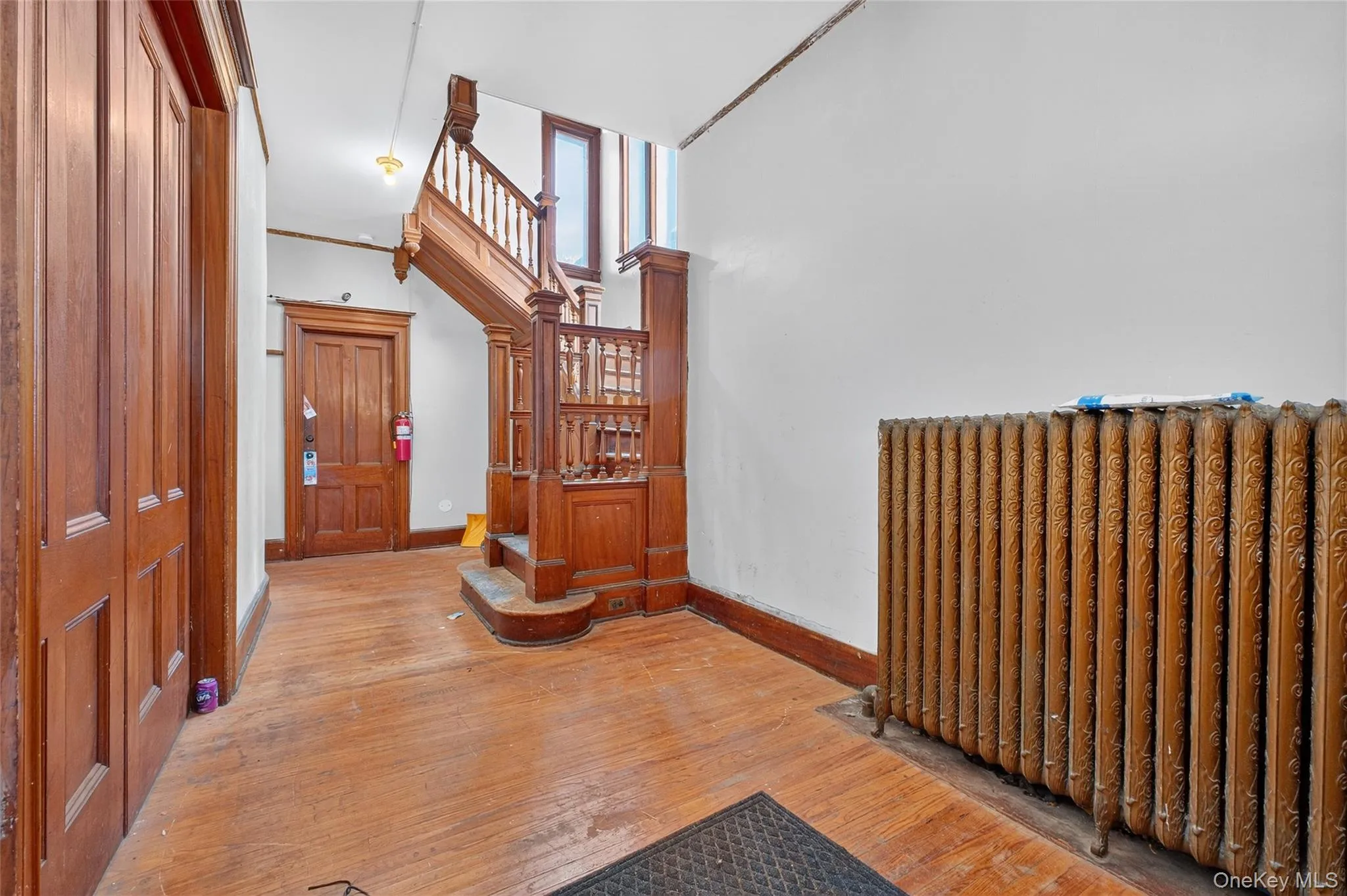 Foyer entrance with radiator, wood-type flooring, and a towering ceiling Foyer entrance with radiator, wood-type flooring, and a towering ceiling