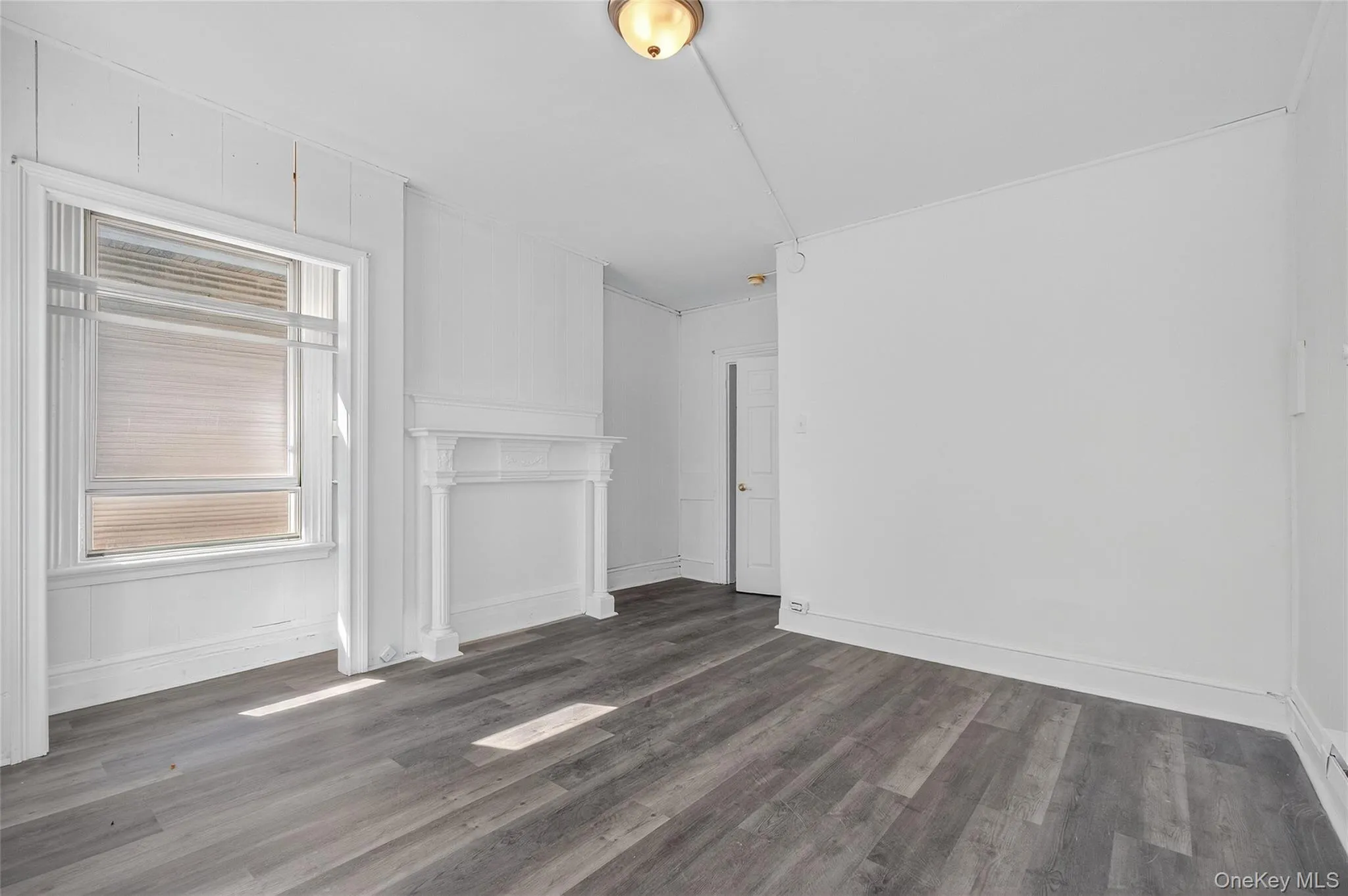 Unfurnished living room featuring dark wood-style floors and baseboards Unfurnished living room featuring dark wood-style floors and baseboards