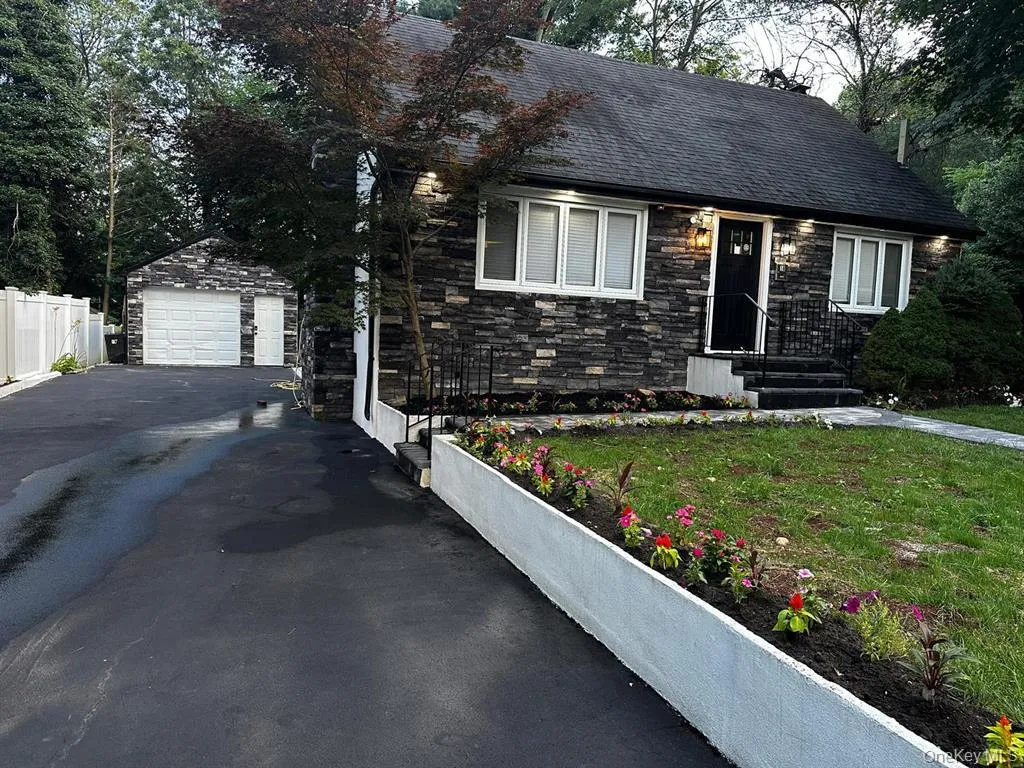 View of front of home featuring stone siding, an outbuilding, a garage, and a shingled roof View of front of home featuring stone siding, an outbuilding, a garage, and a shingled roof