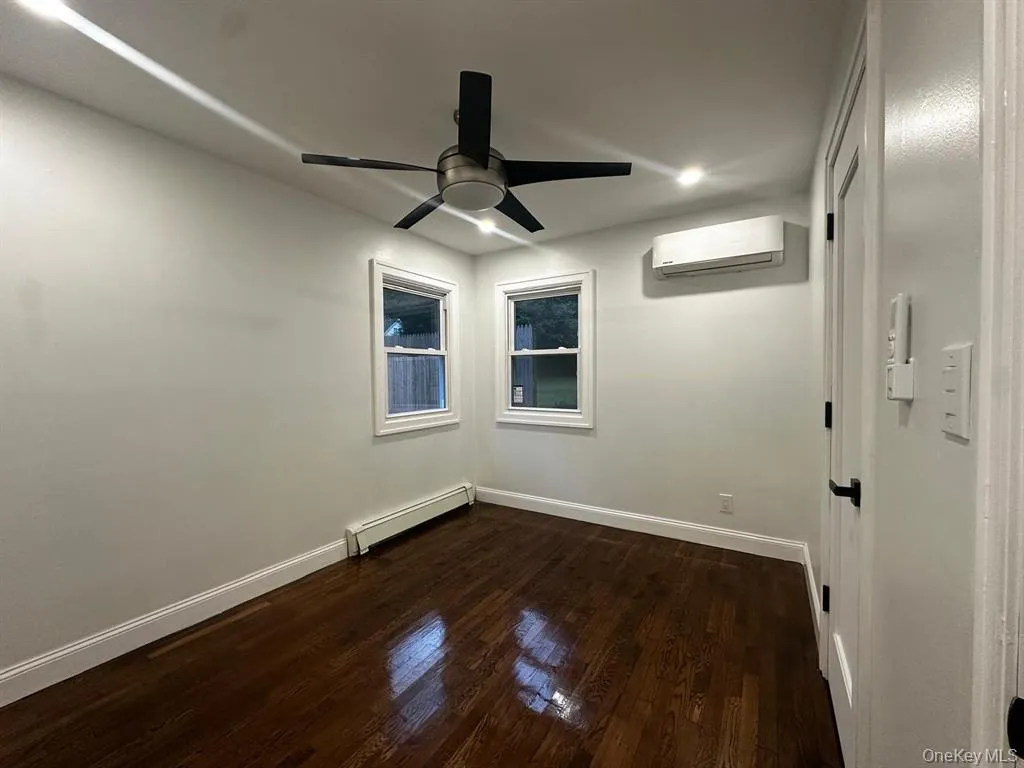 Unfurnished room with a baseboard radiator, dark wood-style flooring, a wall mounted air conditioner, a ceiling fan, and recessed lighting Unfurnished room with a baseboard radiator, dark wood-style flooring, a wall mounted air conditioner, a ceiling fan, and recessed lighting