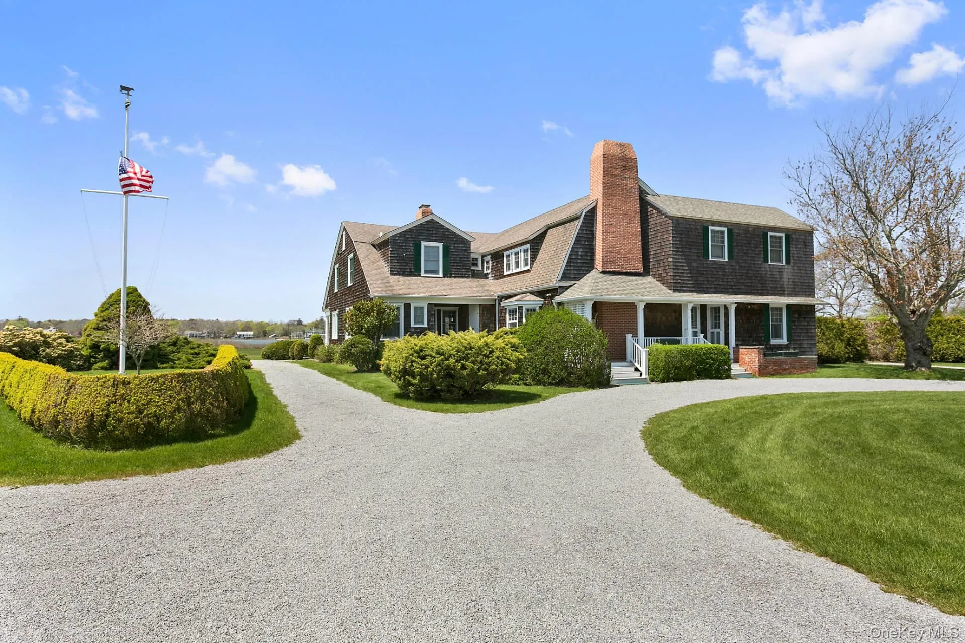 View of front of house featuring covered porch, curved driveway, a chimney, a gambrel roof, and roof with shingles View of front of house featuring covered porch, curved driveway, a chimney, a gambrel roof, and roof with shingles