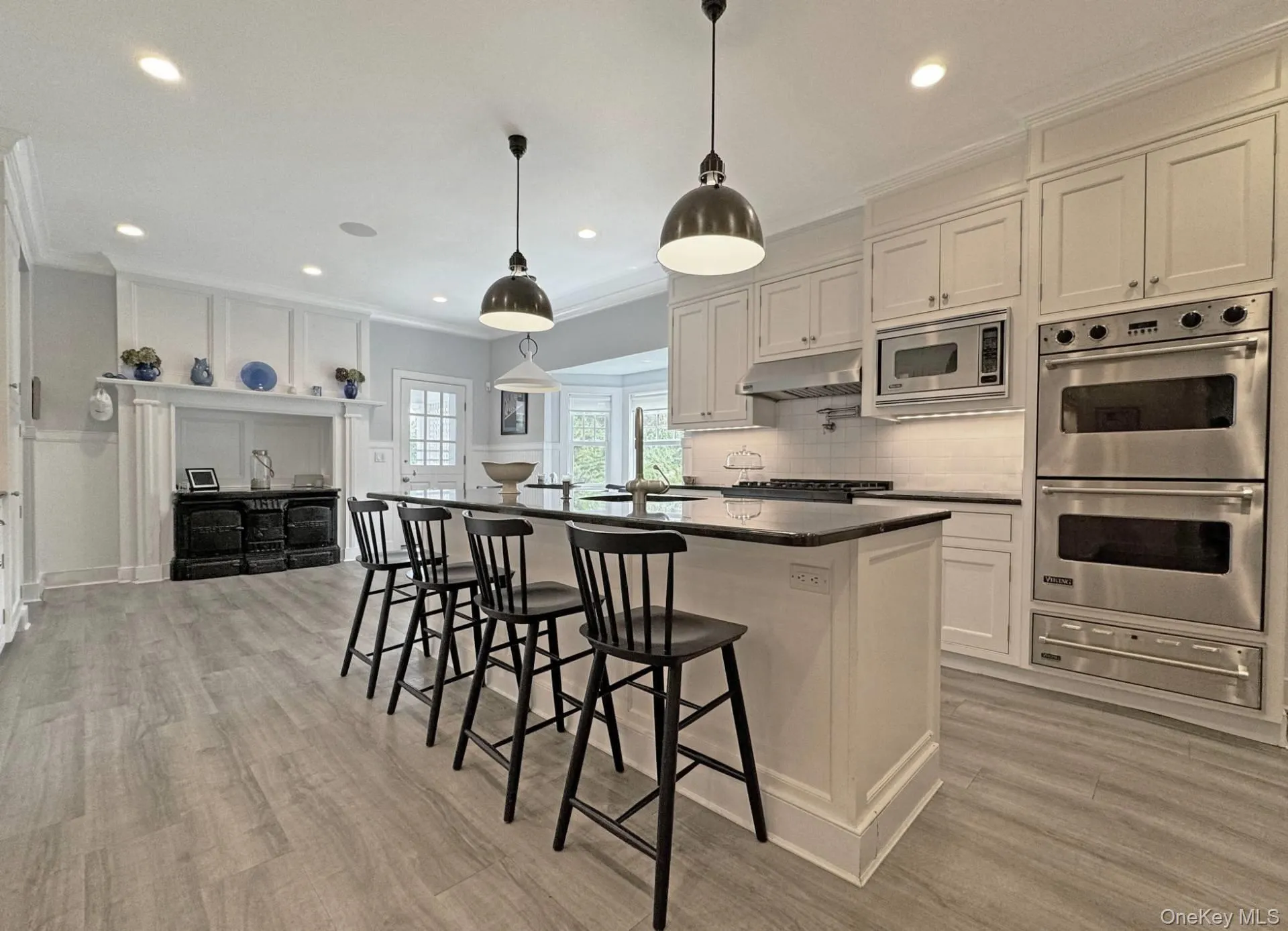 Kitchen with a breakfast bar area, stainless steel appliances, a kitchen island with sink, white cabinetry, and decorative backsplash Kitchen with a breakfast bar area, stainless steel appliances, a kitchen island with sink, white cabinetry, and decorative backsplash