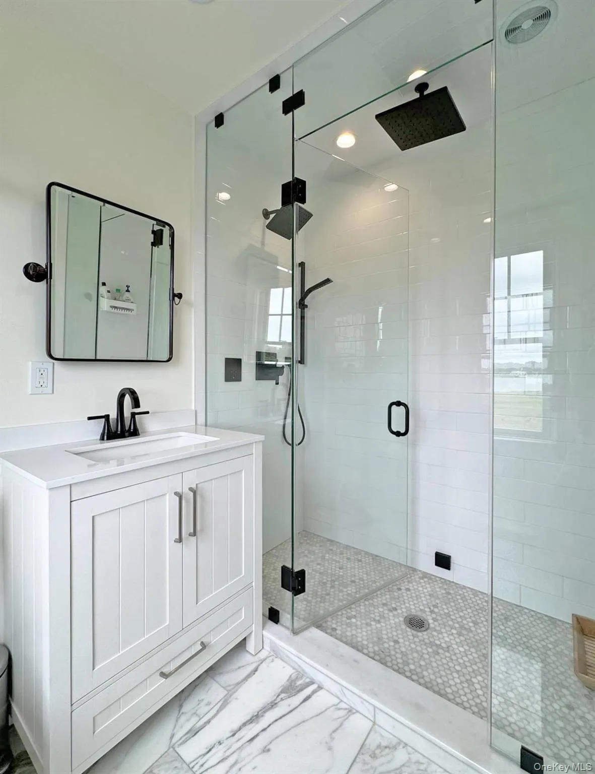 Bathroom featuring vanity, a stall shower, and marble finish flooring Bathroom featuring vanity, a stall shower, and marble finish flooring