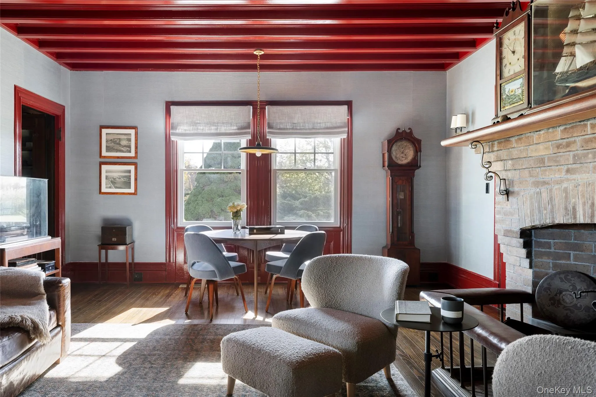 Living room with beamed ceiling, wood-type flooring, and a brick fireplace Living room with beamed ceiling, wood-type flooring, and a brick fireplace