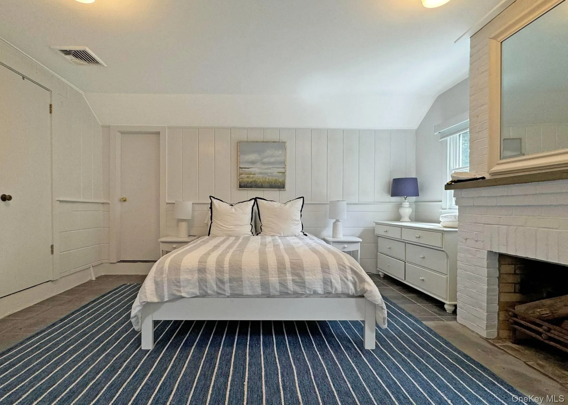 Bedroom with vaulted ceiling, wood walls, and a brick fireplace Bedroom with vaulted ceiling, wood walls, and a brick fireplace