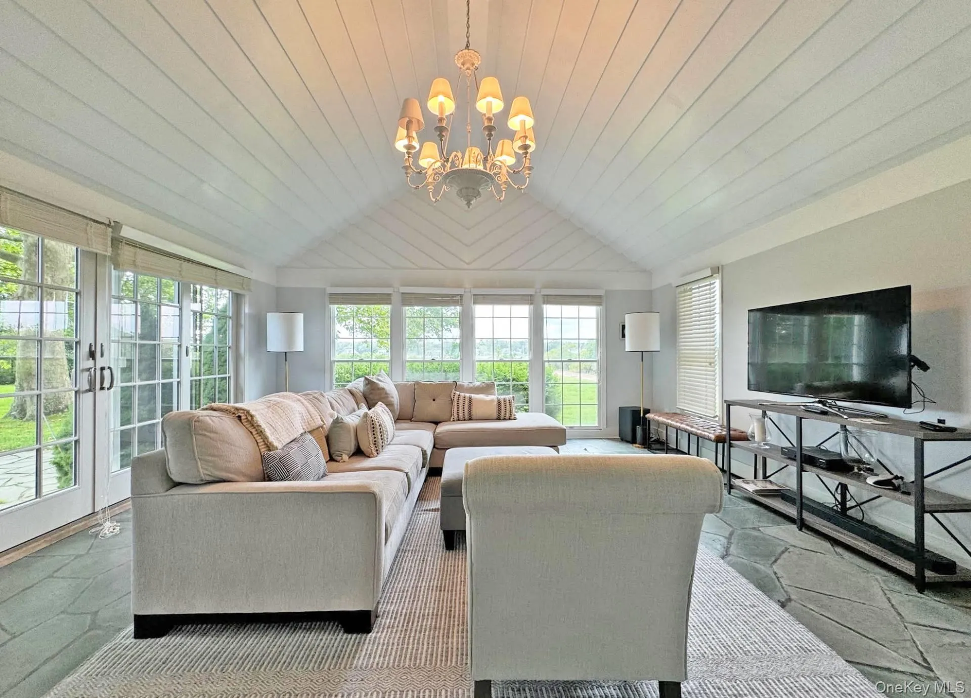 Living area featuring stone tile floors, wooden ceiling, lofted ceiling, and a chandelier Living area featuring stone tile floors, wooden ceiling, lofted ceiling, and a chandelier