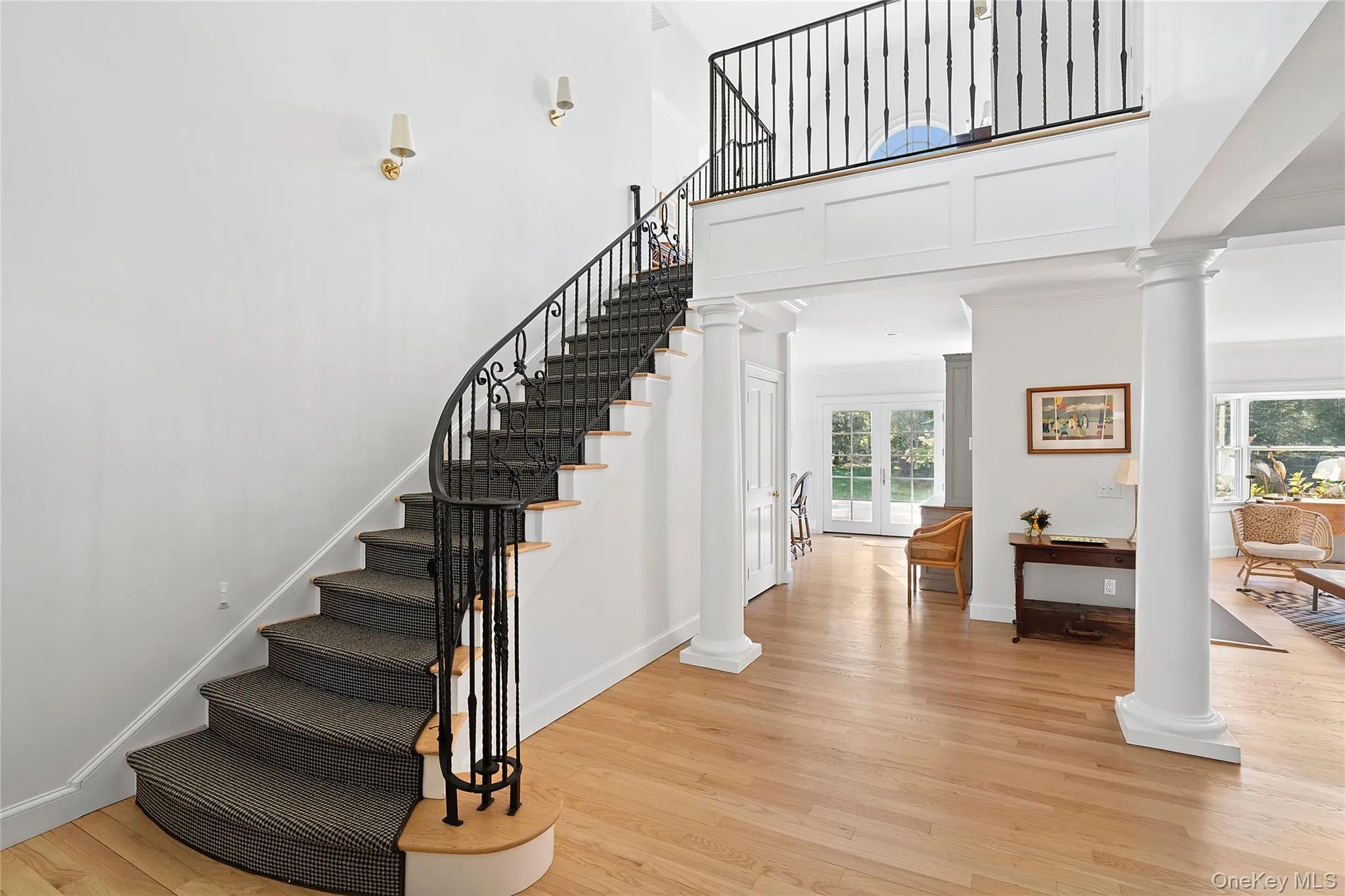 Stairs featuring ornate columns, wood finished floors, and a high ceiling Stairs featuring ornate columns, wood finished floors, and a high ceiling